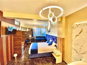 A modern hotel room with a large bed, a desk, and a seating area.