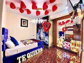 A hotel room with a bed, a heart-shaped balloon, and a message on the bed.