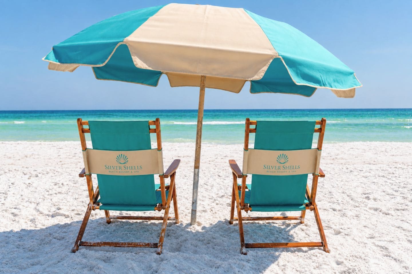Deux chaises de plage et un parasol sur une plage de sable.