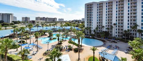A resort with multiple swimming pools, palm trees, and a large building with balconies.