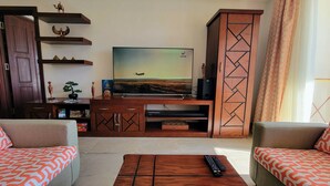 Una sala de estar con televisor, mueble bajo de madera, dos sofás y una mesa de centro.