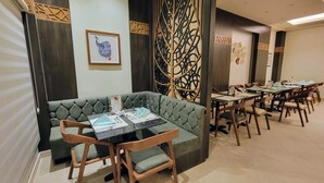 Un comedor con una mesa larga, varias sillas y una zona de estar con cojines.