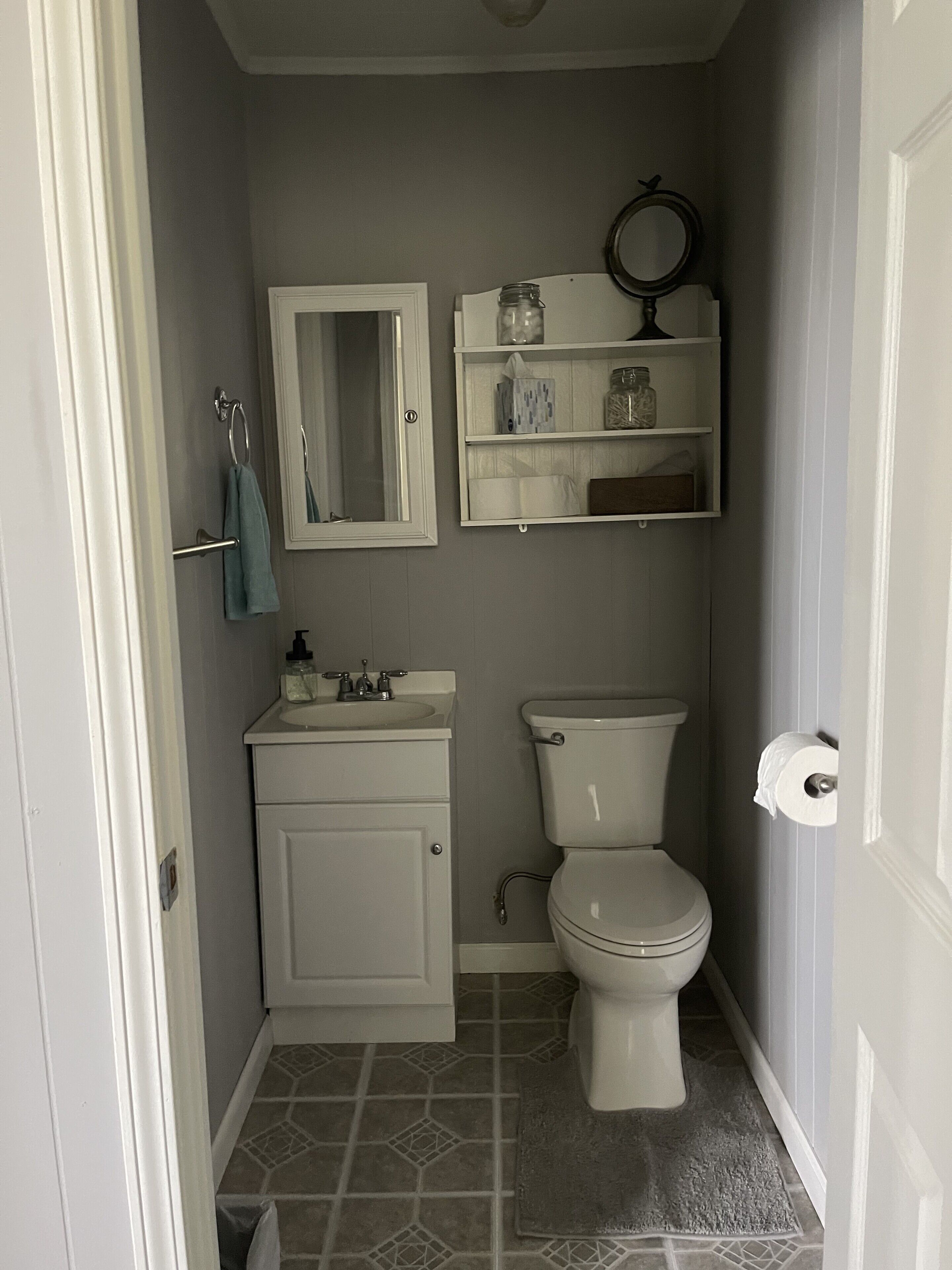 Un baño pequeño con inodoro, lavamanos y espejo.