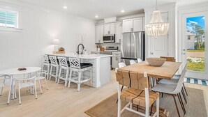 A modern kitchen with white cabinetry, stainless steel appliances, and a central island with seating.
