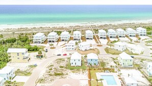 A coastal resort with multiple white buildings, a beach, and a clear view of the ocean.