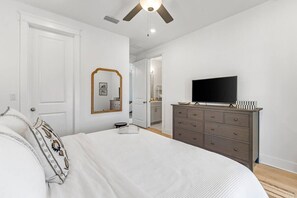 A bedroom with a bed, dresser, television, and a mirror.