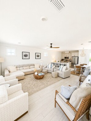 A spacious living room with a large sofa set, a dining area, and a kitchen with modern appliances.