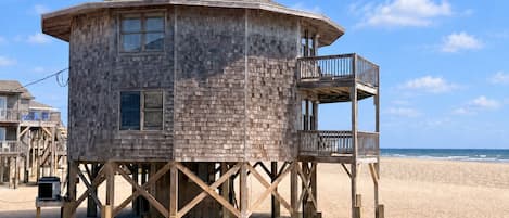 Een houten bewakingstoren met een balkon aan een zandstrand.