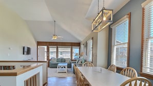 A spacious kitchen with a dining area, wooden furniture, and large windows. - Sea Horse- Oceanside- Only a short Walk to Beach- Community Pool & Spa (Buxton)