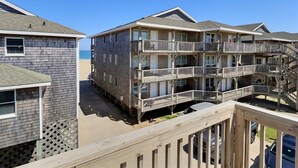 A multi-story beachfront building with balconies and a wooden deck. - Sea Horse- Oceanside- Only a short Walk to Beach- Community Pool & Spa (Buxton)