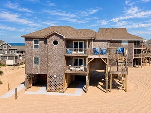 Una proprietà fronte spiaggia su più livelli, con una terrazza inferiore dotata di una scala in legno e terrazze superiori con balconi.