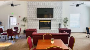 A modern lounge area with a brick fireplace, comfortable seating, and a flat-screen TV mounted above it. - Surestay Hotel By Best Western Eureka (Eureka)