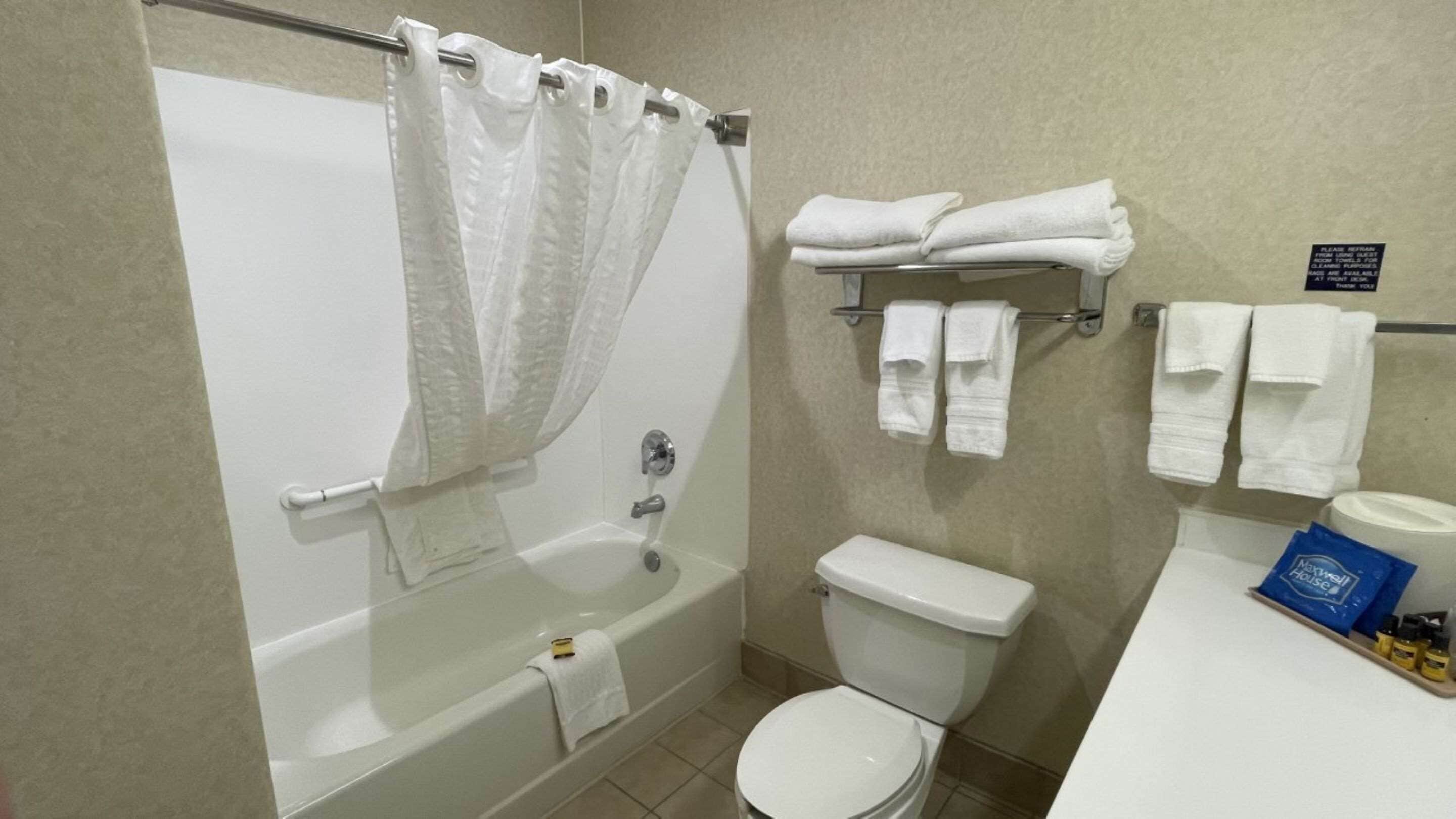 A bathroom with a bathtub, toilet, and a towel rack with folded towels.