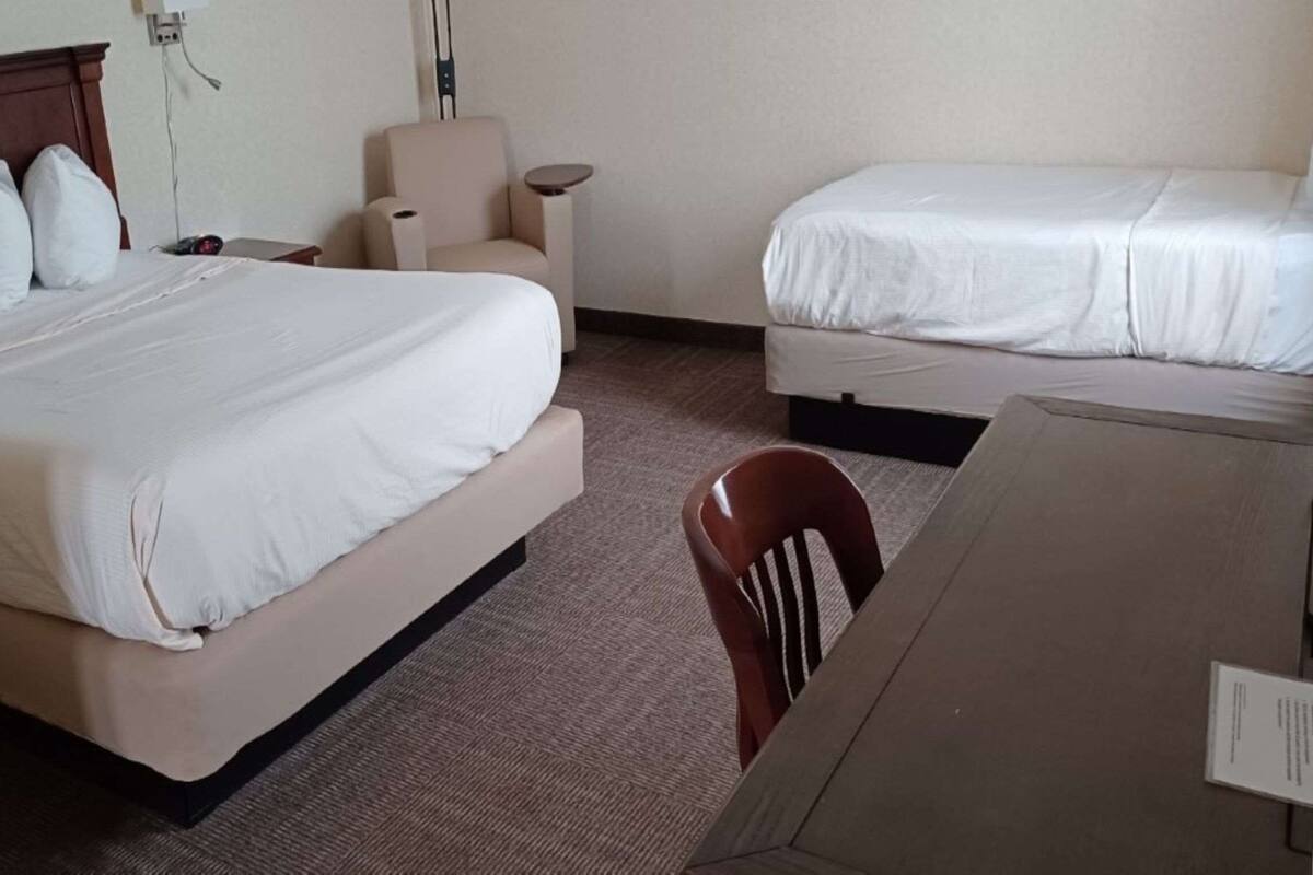 Une chambre d’hôtel avec un grand lit, un lit plus petit, un bureau et une chaise.