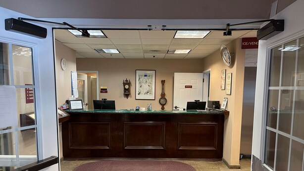 A reception area with a wooden counter, a clock, a framed map, and a door labeled "Ice/Vend". - Surestay Hotel By Best Western Eureka (Eureka)