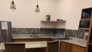 A kitchen with a marble countertop, two wicker bar stools, a built-in stove, and a microwave.