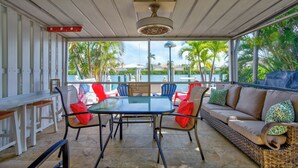 A covered outdoor seating area with a table and chairs, overlooking a body of water and palm trees. - P14 - Charming 2 Bedroom, 2 bath waterfront duplex with Cabana Club. (Key Colony Beach)