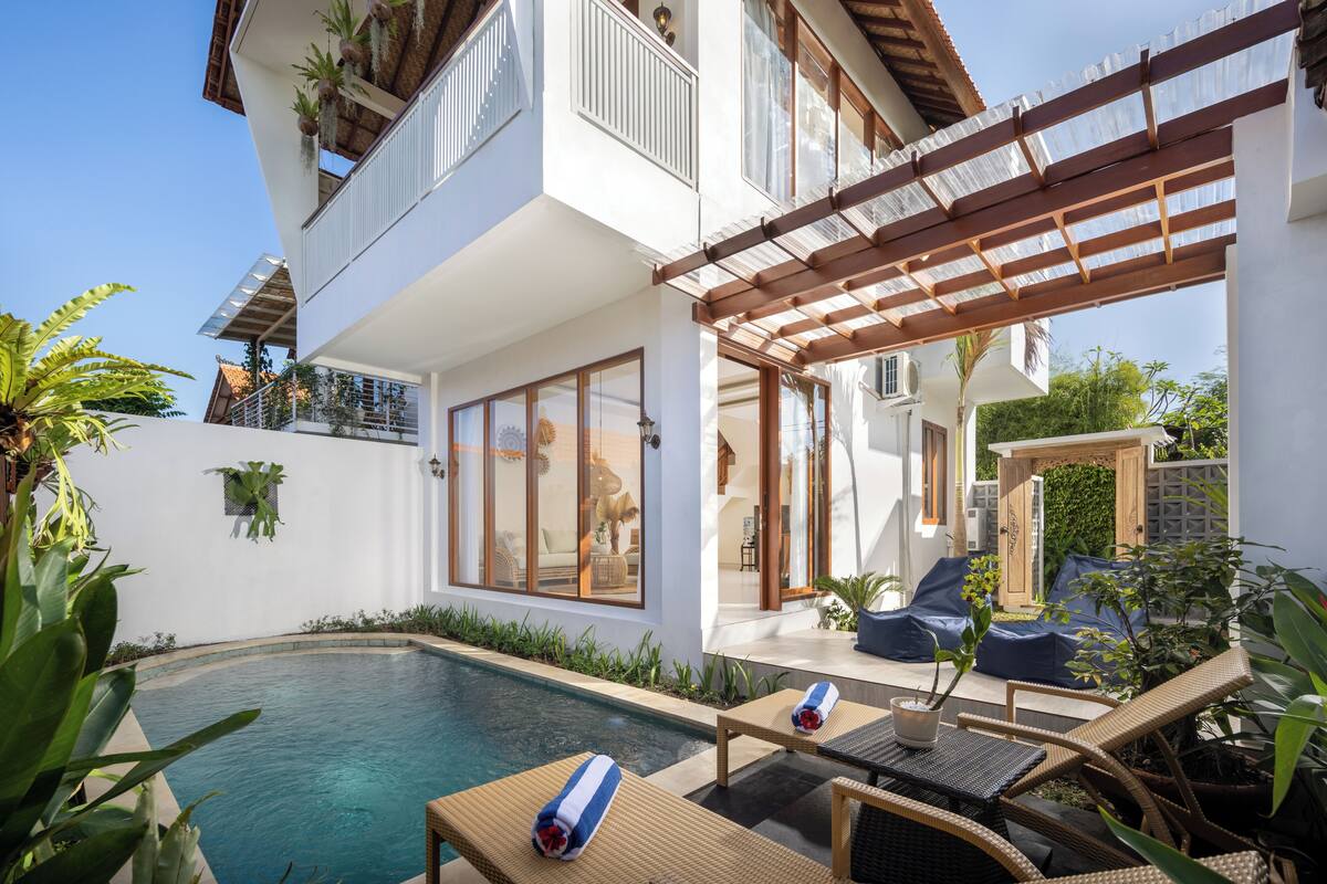 A modern house with a swimming pool, outdoor seating, and a pergola.