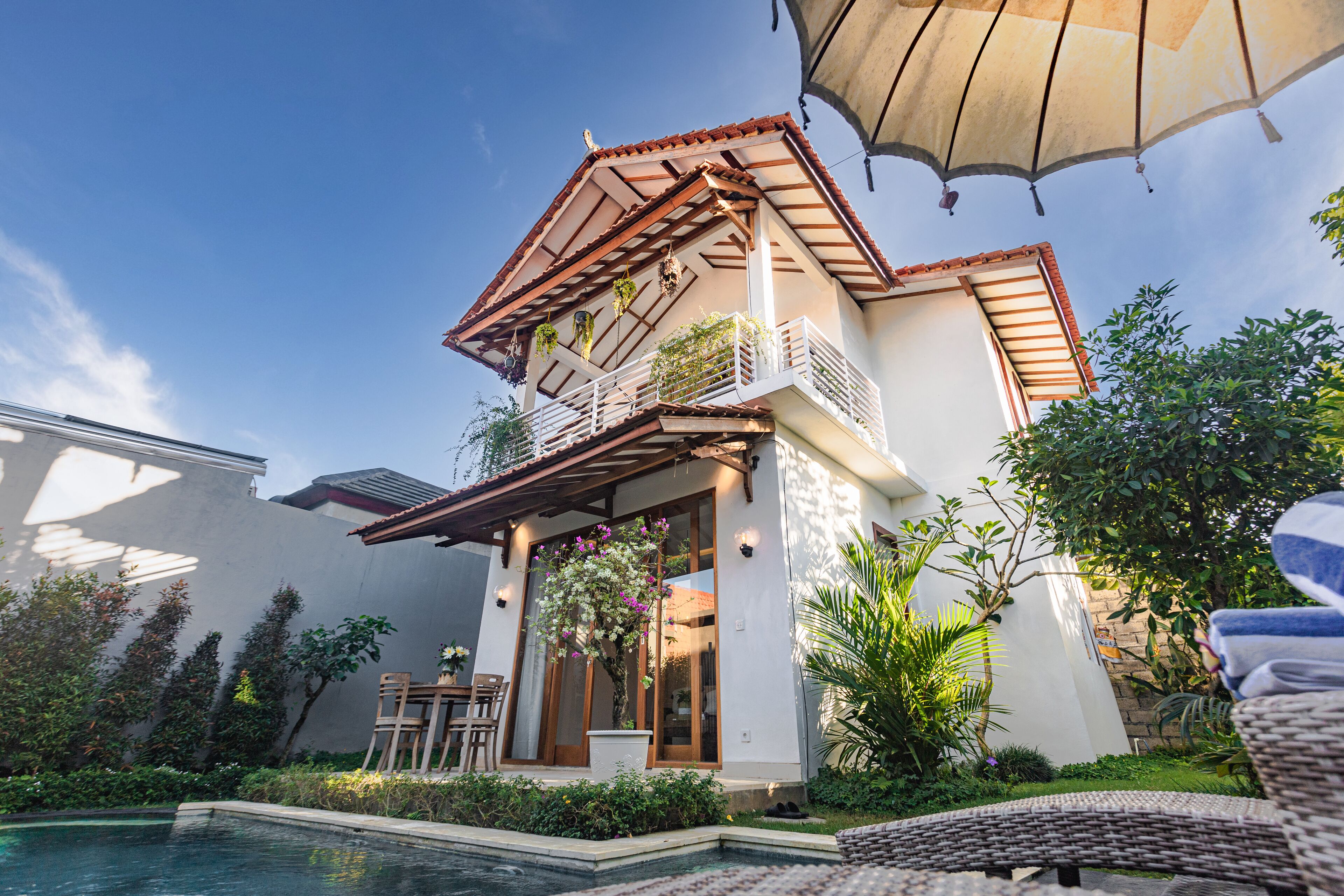 Una casa con piscina, un balcón lleno de plantas y una pérgola.