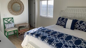 A bedroom with a bed, a chair, a mirror, and a window with blinds. - Beautiful Southwinds condo, oceanfront community with two pools and beach access (Atlantic Beach)