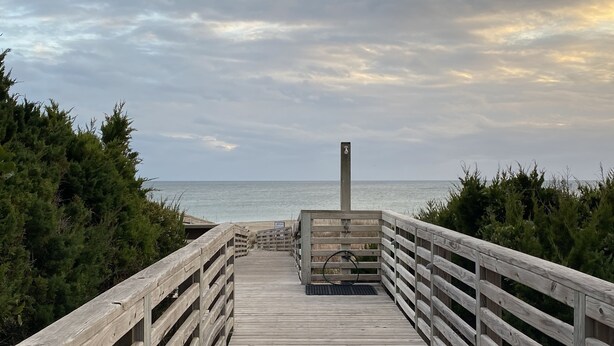 A wooden boardwalk leading to a beach with a wooden post in the center. - Beautiful Southwinds condo, oceanfront community with two pools and beach access (Atlantic Beach)