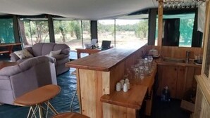 Ein Zeltenbereich im Freien mit einer Bar, Sitzgelegenheiten und Blick ins Grüne.