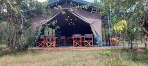 A tent with a table and chairs set up outside, surrounded by trees. - Tents in Masai Mara 2 (Narok)