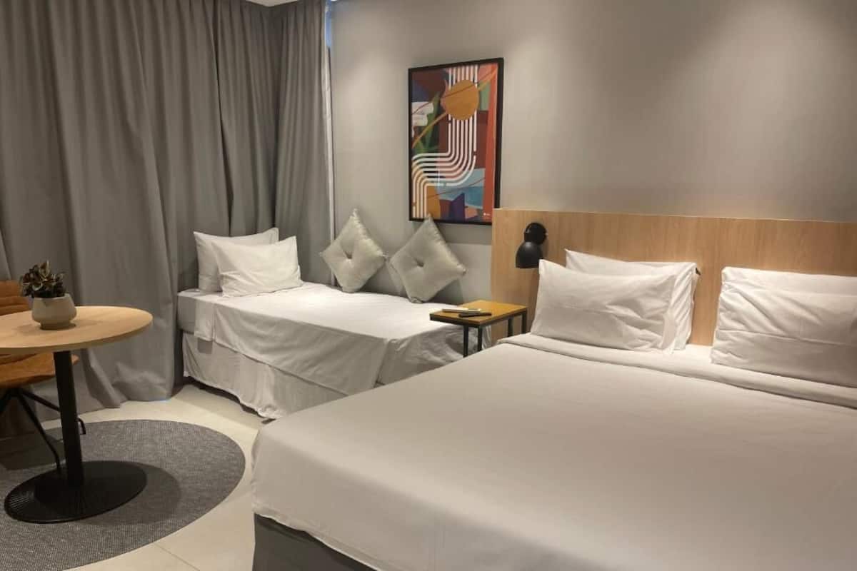 Une chambre d’hôtel avec deux lits, une petite table, une lampe et un tableau au mur.