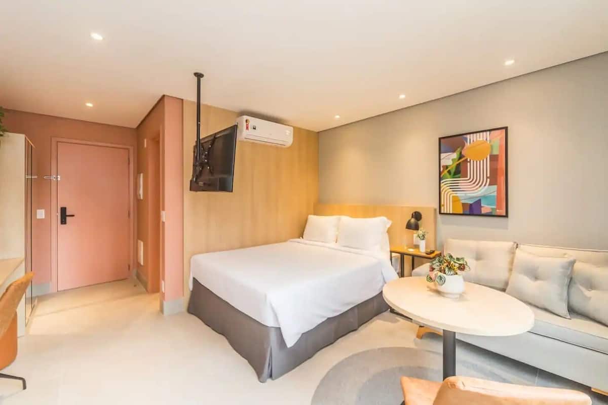 Une chambre d’hôtel moderne équipée d’un lit, d’un canapé, d’une petite table et d’un appareil de climatisation.