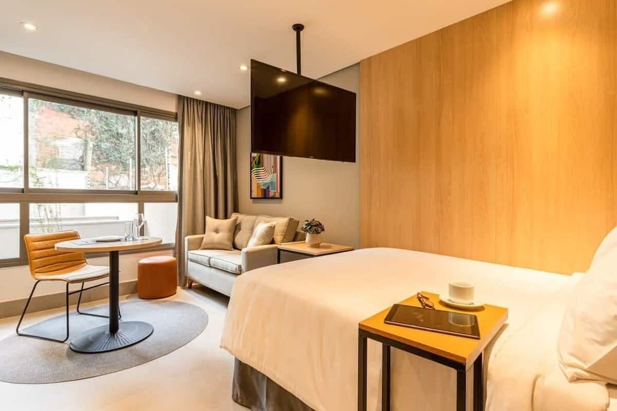 Une chambre d’hôtel moderne, dotée d’un grand lit, d’un canapé, d’une table à manger et d’une fenêtre donnant sur l’extérieur.