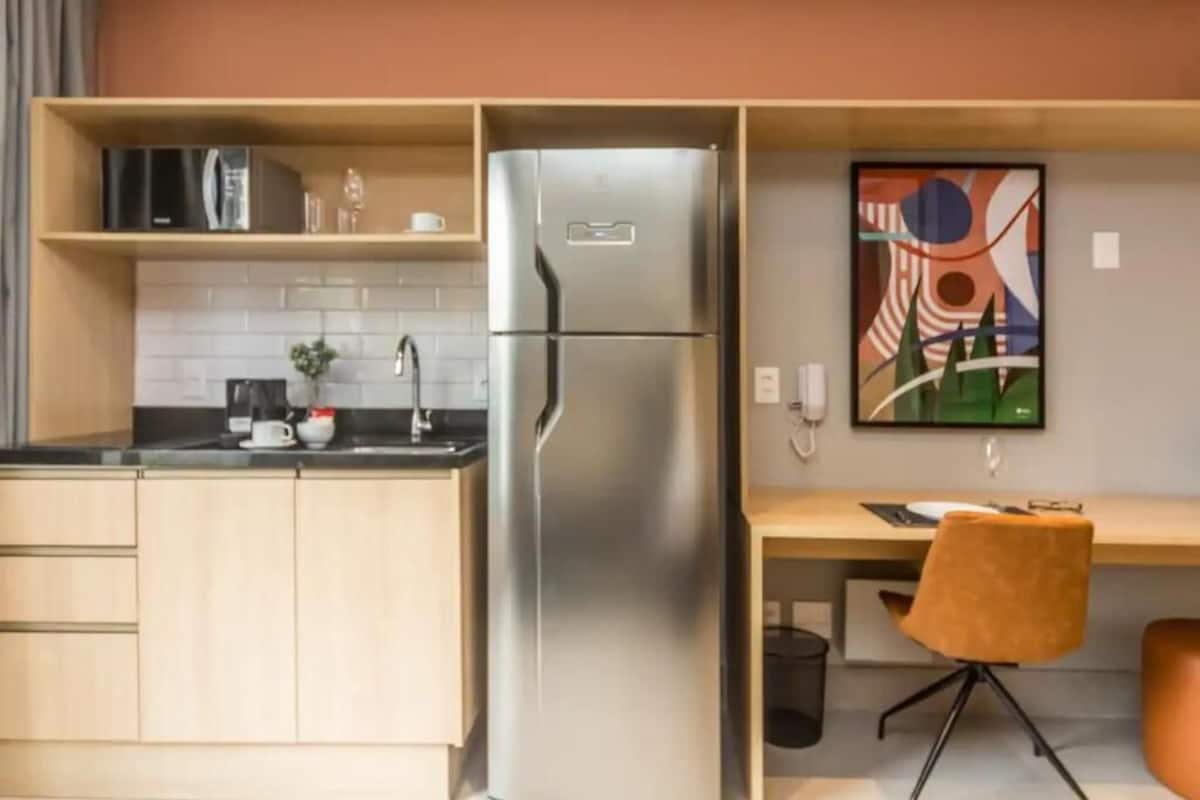 Une cuisine moderne dotée d’un réfrigérateur en acier inoxydable, de meubles de rangement en bois et d’un petit plan de travail sur lequel se trouve une machine à café.