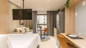 A modern hotel room with a bed, a desk, a chair, a TV, and a window with curtains. - Cozzy Suites Paraiso Hotel (São Paulo)