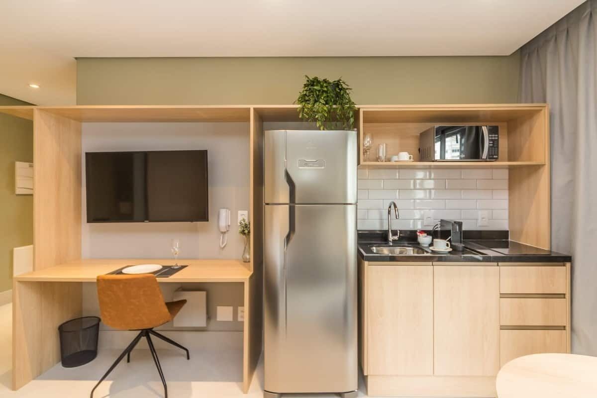 A compact kitchen with a built-in refrigerator, microwave, and a small sink.