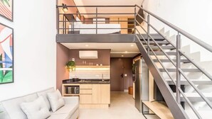 A modern interior with a loft bedroom, a kitchen, and a staircase. - Cozzy Suites Paraiso Hotel (São Paulo)