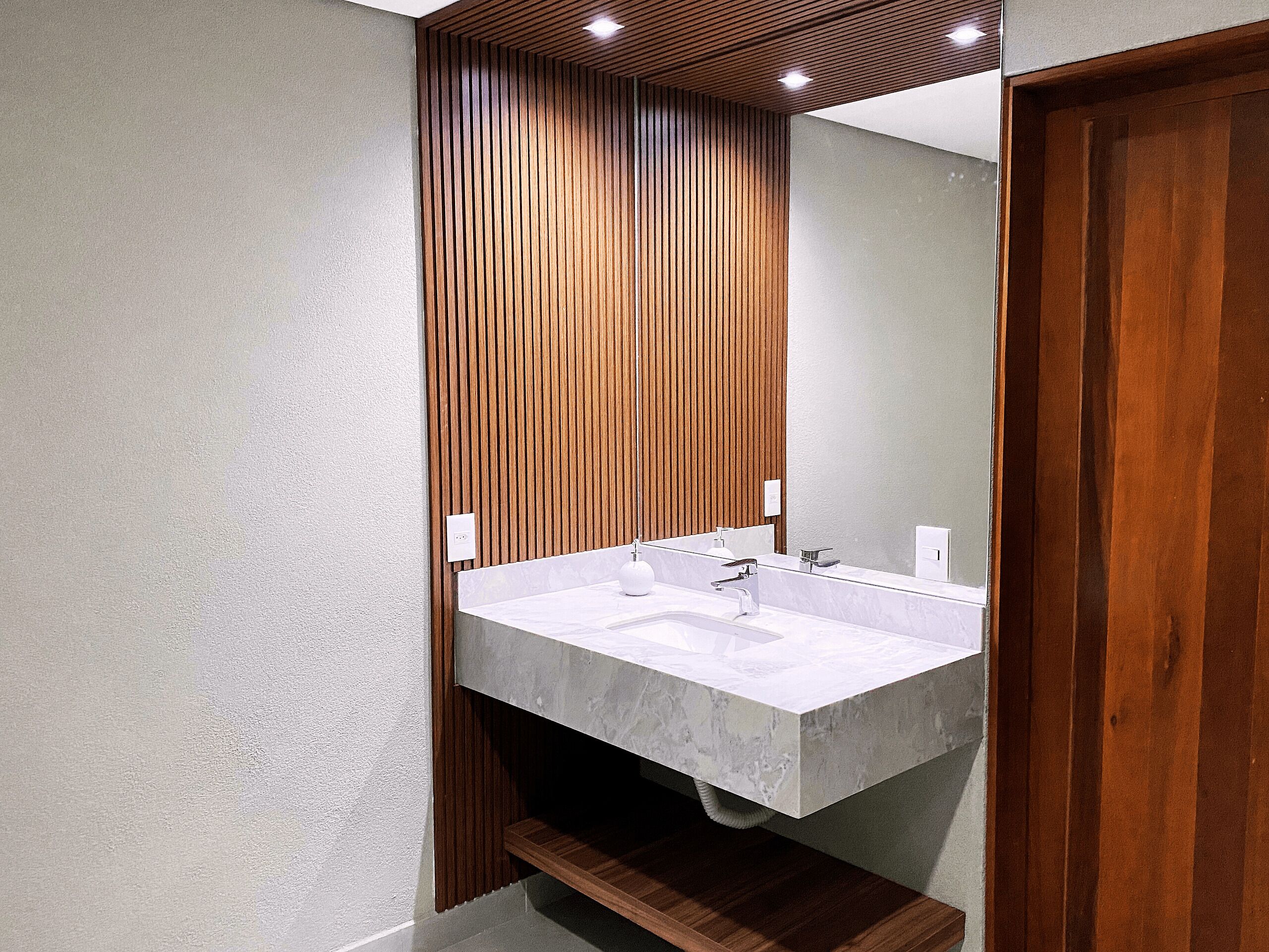 A modern bathroom with a wooden slatted wall, a marble sink, and a large mirror.