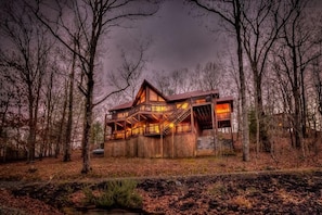 Escape to a secluded cabin surrounded by a forest, featuring a gabled roof and staircase leading to multiple levels.