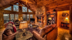 Relax in this inviting living room with a fireplace, leather sofas, and large windows.