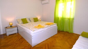 A bedroom with a bed, bedside table, lamp, and a window with curtains. - Room in Lopar with Terrace, Air condition, WIFI (3719-3) (Lopar)