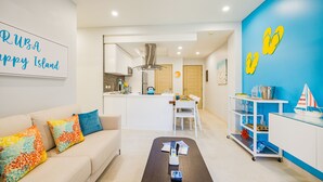 A modern living room with a sofa, coffee table, and a kitchen area in the background. - Aracari Unit-4 Luxurious NEW Apartment (Noord)