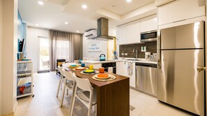 A modern kitchen with a central island, stainless steel appliances, and a dining area with white chairs. - Aracari Unit-4 Luxurious NEW Apartment (Noord)