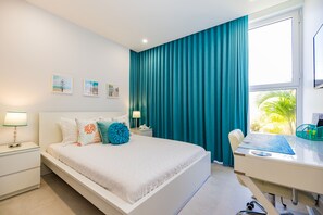 Une chambre moderne avec un grand lit, un bureau et une vue sur des palmiers.