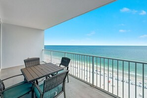 Ein Balkon mit Tisch und Stühlen mit Blick auf einen Strand.
