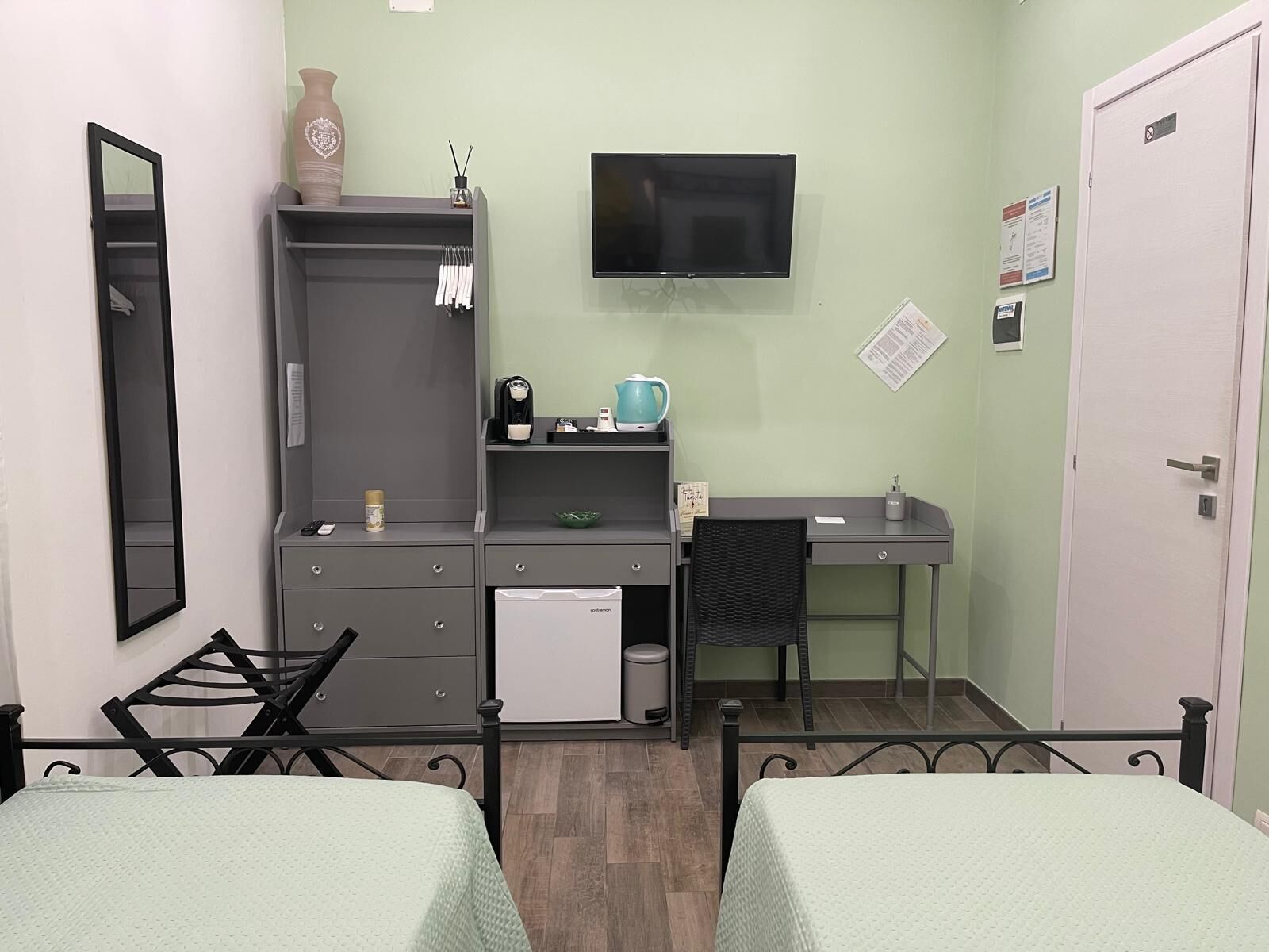 Een compacte, opgeruimde kamer met een bed, bureau, stoel, televisie en kledingkast.