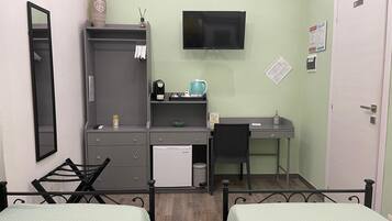 Een compacte, opgeruimde kamer met een bed, bureau, stoel, televisie en kledingkast.