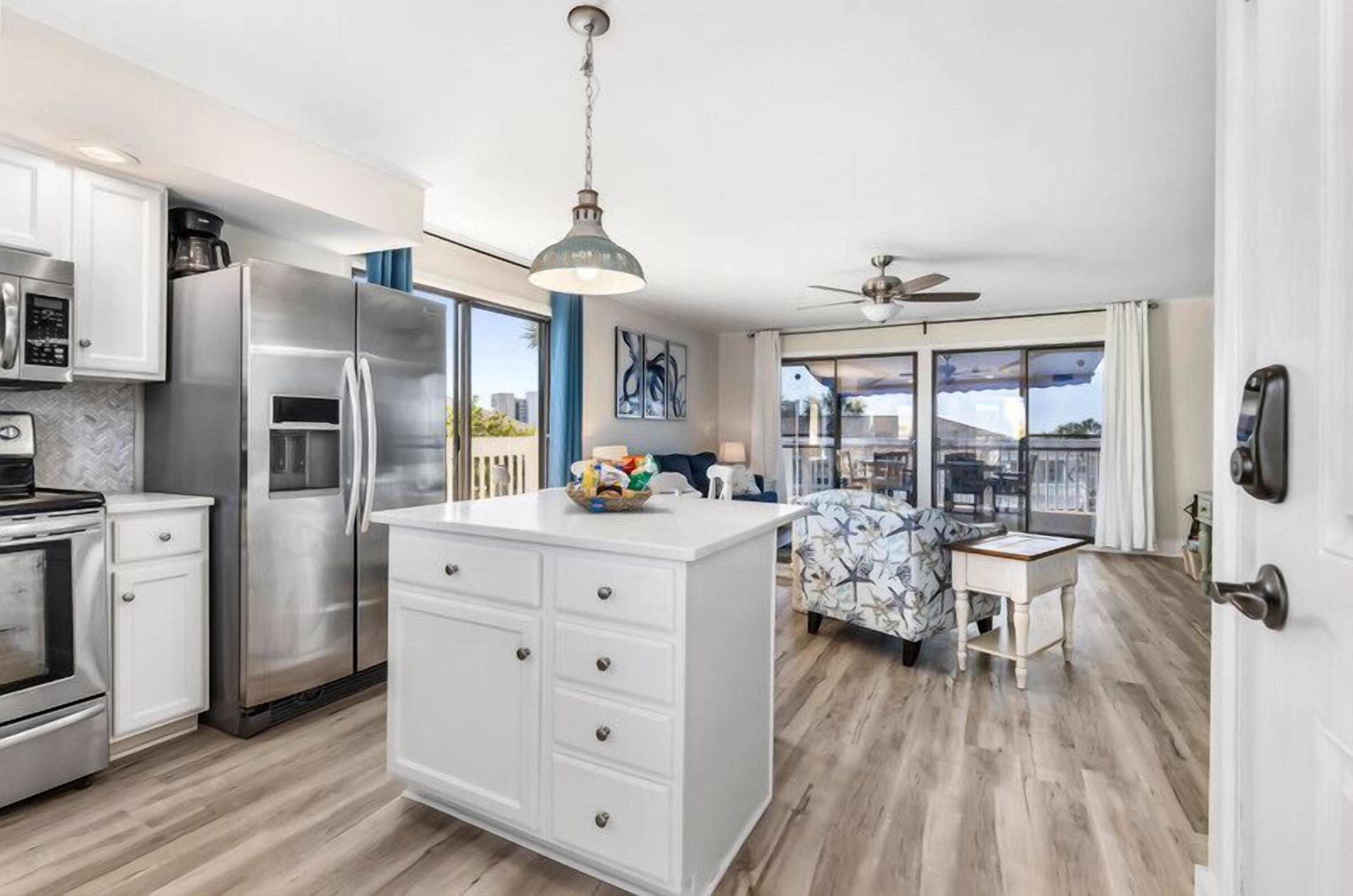 A modern kitchen with stainless steel appliances, a central island, and a dining area with a patterned sofa.