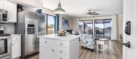 A modern kitchen with stainless steel appliances, a central island, and a dining area with a patterned sofa.