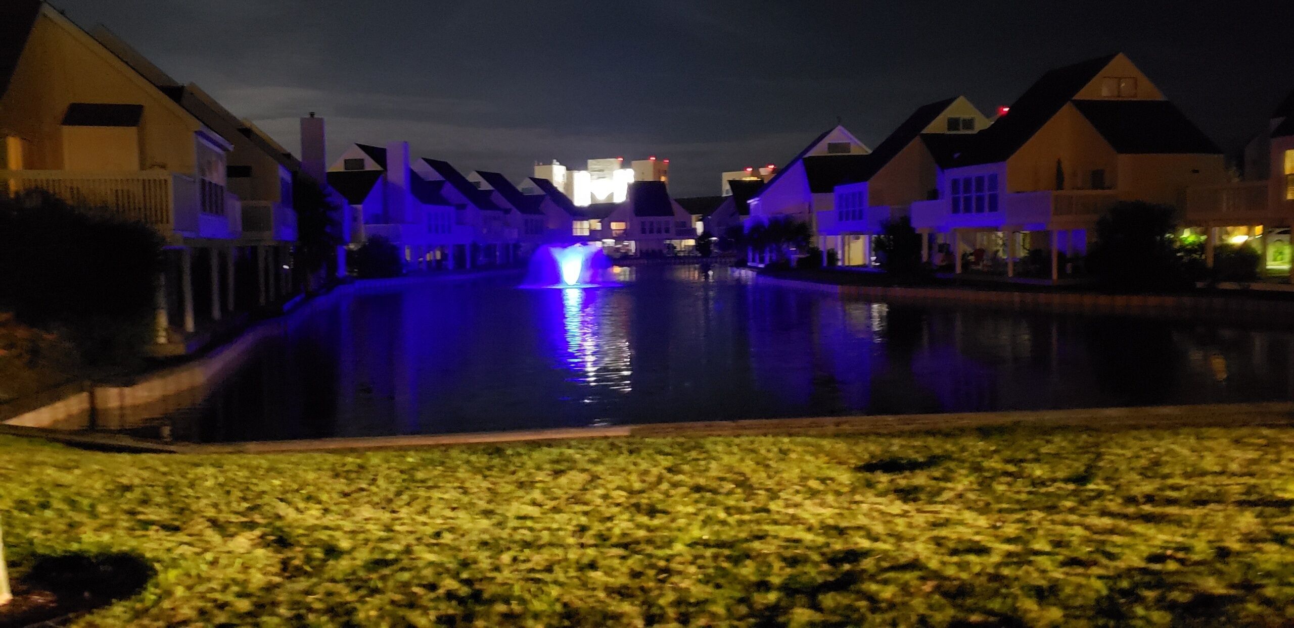 Vista nocturna de una zona residencial con casas alineadas a lo largo de un canal.