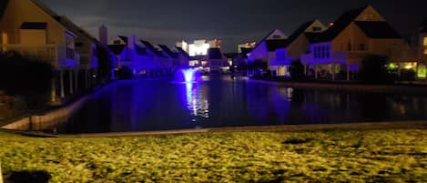 Vista nocturna de una zona residencial con casas alineadas a lo largo de un canal.