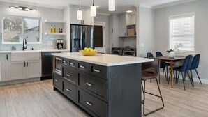 A modern kitchen with a central island, built-in appliances, and pendant lighting. - Luxury Hangout | Private Spa + Game Room + Arcade (Long Beach)