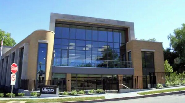 A modern library building with a glass facade, a stop sign, and a sign indicating the library's name.